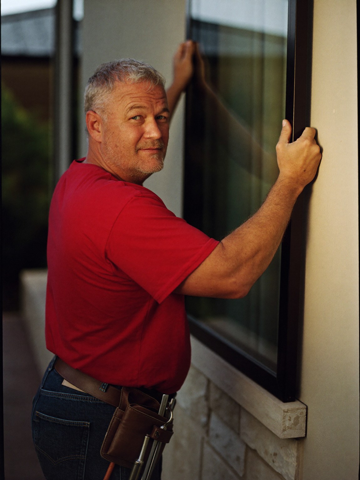 A veteran Spirit of Texas installer in a red shirt setting a window by hand on a Central-Texas home.