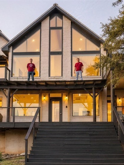 The Hill Country home finished: two crew members in real Spirit of Texas shirts on the upper deck at dusk.